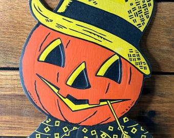 May include: Vintage Halloween decoration of an orange pumpkin head with a yellow and black hat. The pumpkin has black triangle eyes and a yellow mouth with straw. The decoration is set against a wooden background.