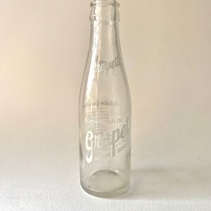 Puede incluir: Una botella de vidrio transparente con una etiqueta blanca que dice "Grapefruit Soda" y "Contains 12 FL. OZ."