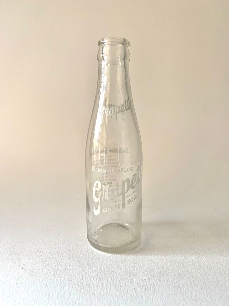 Puede incluir: Una botella de vidrio transparente con una etiqueta blanca que dice "Grapefruit Soda" y "Contains 12 FL. OZ."