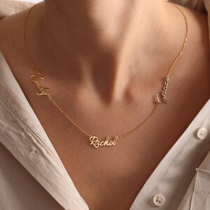 May include: Gold necklace with three names, "Emily", "Rachel", and "Grace", written in cursive.