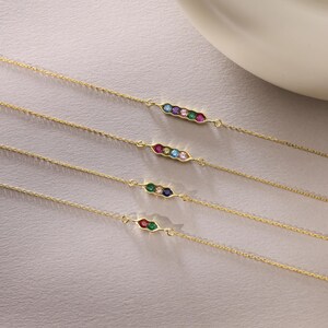 May include: Four gold chain bracelets with a pea pod design featuring colorful gemstones. Each bracelet has a different combination of gemstones, including red, blue, green, and pink.