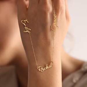May include: Gold necklace with three names, "Emily", "Rachel", and "Grace", written in cursive.