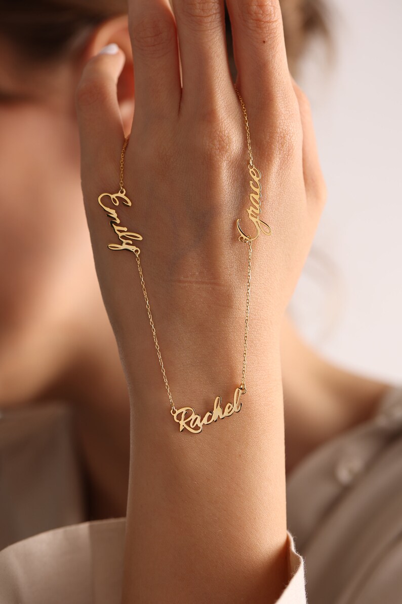 May include: Gold necklace with three names, "Emily", "Rachel", and "Grace", written in cursive.
