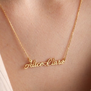 May include: Gold necklace with the names "Alice" and "Clara" connected by a heart symbol.