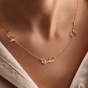 May include: Gold necklace with three names, "Emily", "Rachel", and "Grace", spelled out in cursive.