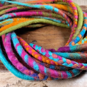 Könnte beinhalten: Nahaufnahme eines Bündels bunter Wolldreadlocks. Die Dreadlocks bestehen aus verschiedenen Farben, darunter Pink, Blau, Grün und Orange. Sie sind kreisförmig angeordnet, und die Enden der Dreadlocks sind sichtbar.