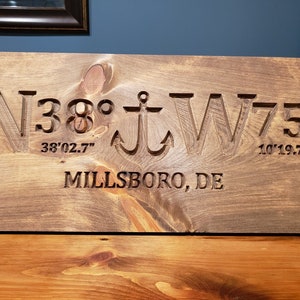 May include: A wooden sign with the coordinates N38&deg; 38'02.7" W75&deg; 10'19.7" and the text "Millsboro, DE" carved into it.