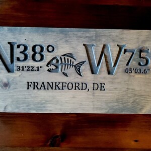 May include: A wooden sign with the coordinates N38&deg;31'22.1" W75&deg;05'03.6" and the text "Frankford, DE".