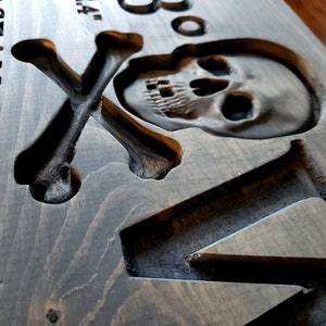 May include: A wooden sign with a carved skull and crossbones design. The sign reads "Ocean City MD" and has a distressed, rustic look.