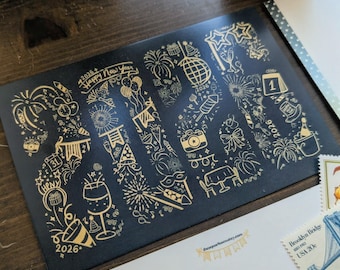 May include: A black greeting card with gold illustrations of fireworks, champagne glasses, and other New Year's Eve symbols. The card has the text "2026 Happy New Year" and other dates. Other stationery items are in the background.