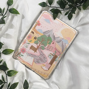 以下が含まれることがあります： ピンク色の納屋、山、朝日を描いたカラフルなイラストが特徴の透明な携帯電話ケース。 デザインには、川、カウボーイブーツ、テキスト「Looking for my cowboy」が含まれています。 ケースは長方形で、透明なボーダーが付いています。