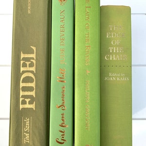 Peut inclure: Quatre livres à couverture rigide de couleur verte. Les titres dorés sur les dos des livres incluent "FIDEL", "The Girl from Summer Hill", "The Lady of the Rivers" et "The Edge of the Chair". Les livres sont disposés verticalement.