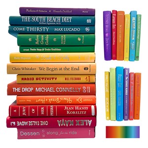 May include: A collection of colorful books stacked together, showcasing a spectrum of hues from purple to pink. Titles and authors are visible on the spines, including "The South Beach Diet" and "Come Thirsty."