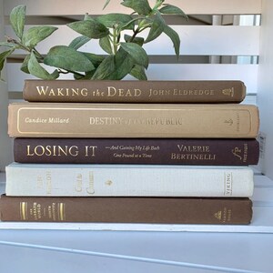 May include: A stack of five brown, beige, and white hardcover books with gold lettering. The titles are "Waking the Dead", "Destiny of the Republic", "Losing It", "Out to Canaan", and "The Sabbath World".