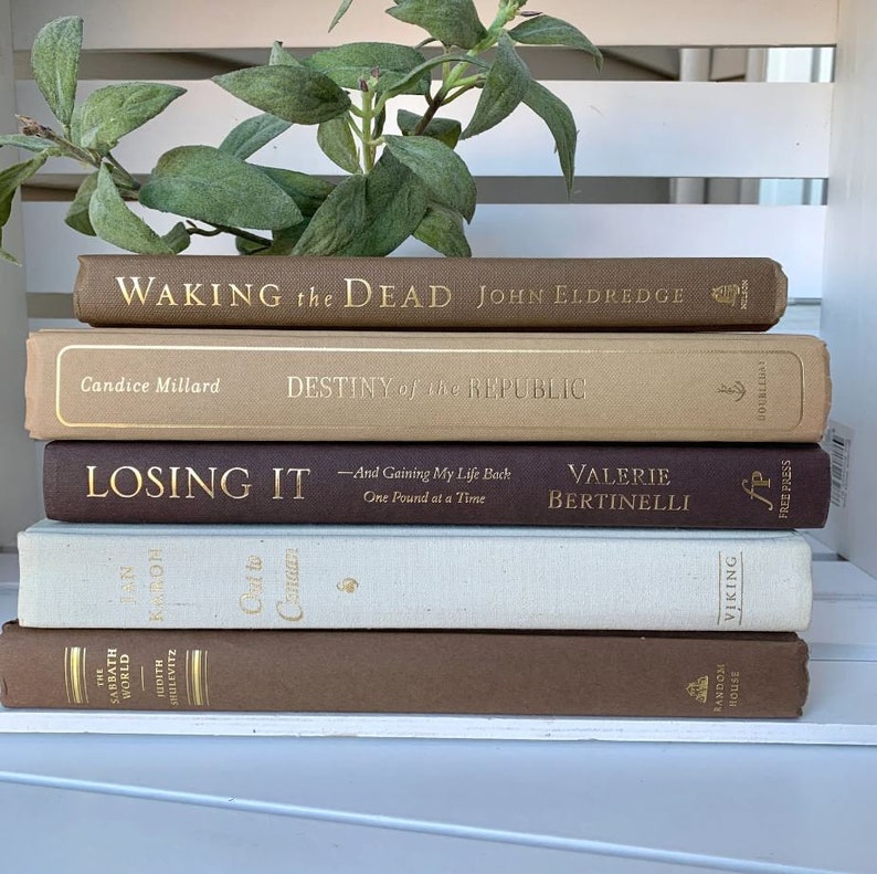 May include: A stack of five brown, beige, and white hardcover books with gold lettering. The titles are "Waking the Dead", "Destiny of the Republic", "Losing It", "Out to Canaan", and "The Sabbath World".