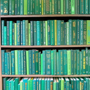 May include: A bookshelf filled with green and teal colored books. The books are arranged in rows and are all different sizes. The books are all spine-out and the titles are visible.