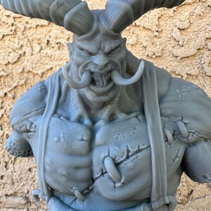 May include: A gray 3D printed bust of a demon with horns, a large mouth, and a stitched-up chest.