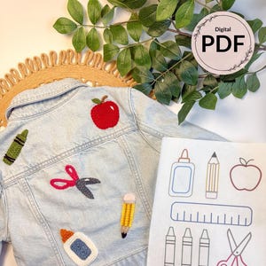 May include: Light blue denim jacket with embroidered school-themed patches, including a red apple, scissors, and crayons. A matching digital PDF with school supply illustrations is next to the jacket. The jacket is a children's size.