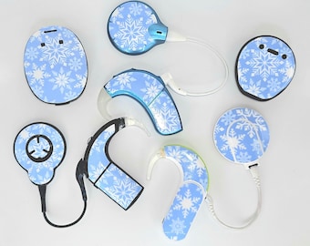 Può includere: Una collezione di apparecchi acustici e accessori, con un motivo a fiocchi di neve azzurri. I dispositivi variano in forma e dimensione, inclusi modelli retroauricolari e componenti intrauricolari più piccoli. L'estetica generale è pulita e moderna.