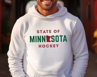 Pode incluir: Hoodie branco com um gráfico vermelho, verde e branco que diz "State of Minnesota Hockey" com um contorno do estado de Minnesota em vermelho.