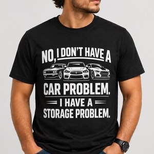 Puede incluir: Camiseta negra con el texto "NO, I DON'T HAVE A CAR PROBLEM. I HAVE A STORAGE PROBLEM." El diseño incluye ilustraciones de tres coches. El texto es blanco.