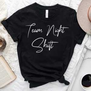 Puede incluir: Camiseta negra con texto blanco que dice "Team Night Shift".