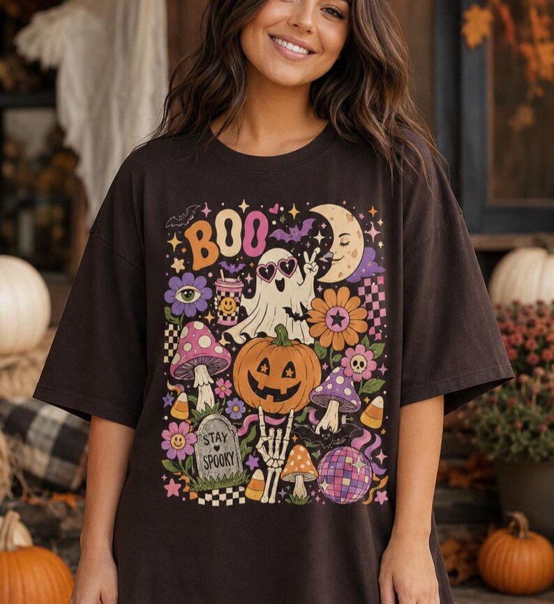 Woman wearing a purple Halloween T-shirt featuring a cute ghost, pumpkin, mushrooms, flowers, moon and colorful retro artwork.