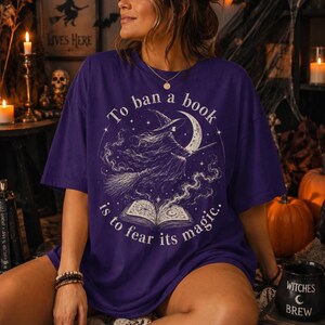 Witchy book lover Halloween shirt graphic with flying witch, moon, magical stars and open book in a distressed vintage style.
