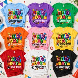 May include: Nine colorful t-shirts with the words "Field Day" in a playful design. Each shirt is a different color, including blue, purple, green, orange, pink, yellow, red, white, and black, with team names.