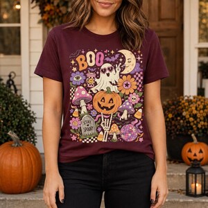 Cute spooky season T-shirt with colorful ghost, pumpkin, crescent moon, flowers, candy corn and disco ball design.
