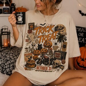 Woman wearing an oversized dark green Halloween t-shirt featuring a vintage Trick or Treat graphic with pumpkins, ghosts, skeletons, bats and October 31 text.