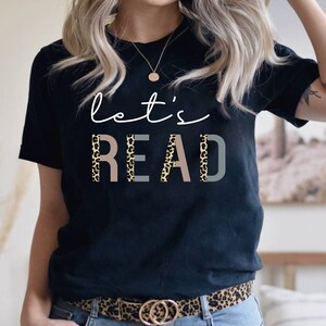 May include: Black t-shirt with the text "let's READ" in white with a leopard print pattern behind the letters.