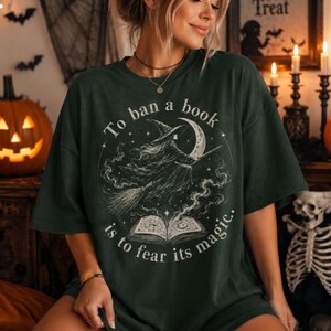 Retro Halloween witch t-shirt design with broomstick witch, crescent moon, spell book and gothic “To ban a book is to fear its magic” text.