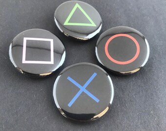 May include: Four glossy black buttons with iconic gaming symbols: a green triangle, a pink square, a red circle, and a blue X. These buttons are arranged in a circular pattern, likely for a gaming console controller.