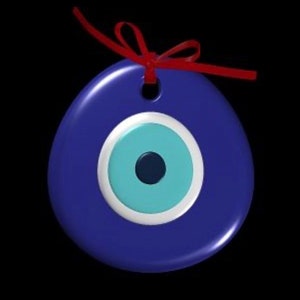 Puede incluir: Un amuleto de ojo turco azul y blanco con una cinta roja atada en la parte superior. El amuleto es un símbolo popular de protección contra el mal de ojo.