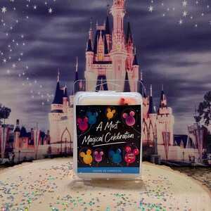 May include: A white candle with a black label that says "A Most Magical Celebration" with Mickey Mouse balloons and the text "50 Years of Magic". The candle is in front of a picture of Cinderella's Castle.
