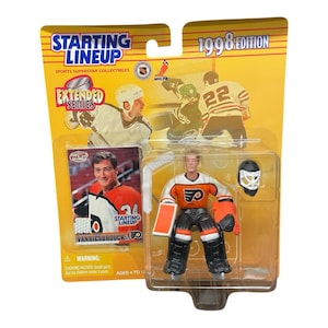 May include: A 1998 Edition Starting Lineup hockey figure of John Vanbiesbrouck in a Philadelphia Flyers uniform. The figure is in a plastic case with a card and the words "Starting Lineup" and "Extended Series" on the packaging.