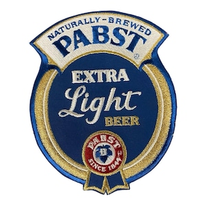 May include: A blue, gold, and white Pabst Extra Light Beer patch. The patch is shield-shaped with the words "NATURALLY-BREWED PABST" at the top. The words "EXTRA Light BEER" are in the center. A small Pabst logo is at the bottom.