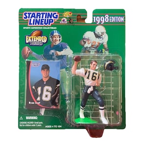 May include: A 1998 edition Starting Lineup sports collectible. The packaging features a football player figurine in a white and black uniform, with the number 16. Includes a card with a photo of Ryan Leaf and the text "Starting Lineup".
