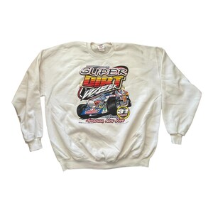 May include: Off-white sweatshirt featuring a colorful graphic of a race car with the text "SUPER DIRT WEEK" and "Syracuse, New York". The graphic includes red, orange, blue, and yellow accents. The sweatshirt has a crew neck and long sleeves.
