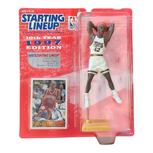 May include: A Starting Lineup 1997 edition action figure of Jerry Stackhouse in a Philadelphia 76ers uniform, with a matching trading card. The packaging is red with the words "Starting Lineup" and "1997 Edition".
