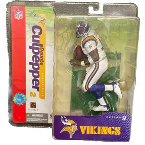May include: A plastic action figure of Daunte Culpepper, a Minnesota Vikings quarterback, in a white and purple uniform. The figure is posed in a running position with the football in his hand. The figure is packaged in a clear plastic box with a purple and yellow background. The box has the words "Culpepper 2" and "Vikings" on it.