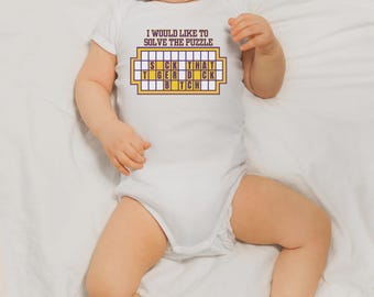May include: White baby onesie with the text "I WOULD LIKE TO SOLVE THE PUZZLE" above a puzzle board that spells out "SICK THAT TIGER DICK BITCH" in purple and yellow. The baby is lying on a white sheet.