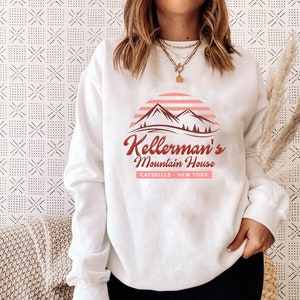 May include: White sweatshirt with a red and pink graphic design featuring mountains, a sunset, and the text "Kellerman's Mountain House Catskills - New York".
