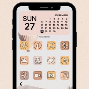 May include: A smartphone screen displaying a calendar widget with the date "SUN 27" and the month "SEPTEMBER". The calendar is surrounded by a hot air balloon graphic. Below the calendar are nine app icons with various colors and designs, including a Pinterest icon, a Facebook icon, a Google icon, a flower icon, a cloud icon, an Amazon icon, a heart icon, a target icon, a location icon, a video camera icon, a camera icon, and an Instagram icon.