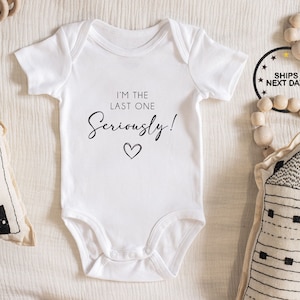 May include: White baby onesie with black text that reads "I'm the last one Seriously!" with a small heart below the text.