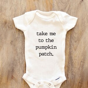 May include: White baby onesie with black text that reads "take me to the pumpkin patch."