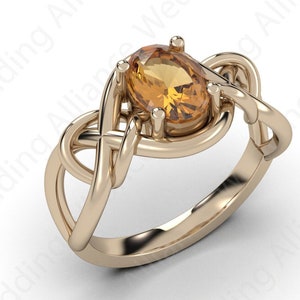 May include: A gold ring with a Celtic knot design and a large oval-shaped topaz gemstone.