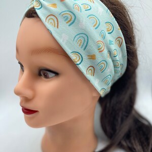 May include: A light blue headband with a pattern of colorful rainbows and white teeth. The headband is made of a soft, stretchy fabric and is perfect for keeping hair out of your face.
