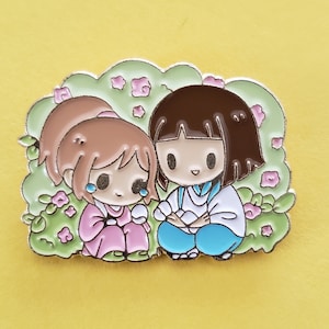 May include: Two cartoon characters, a girl with brown hair and a girl with brown hair, are sitting in a field of pink flowers. The girl with brown hair is wearing a pink dress and has tears on her cheeks. The girl with brown hair is wearing a blue and white dress.